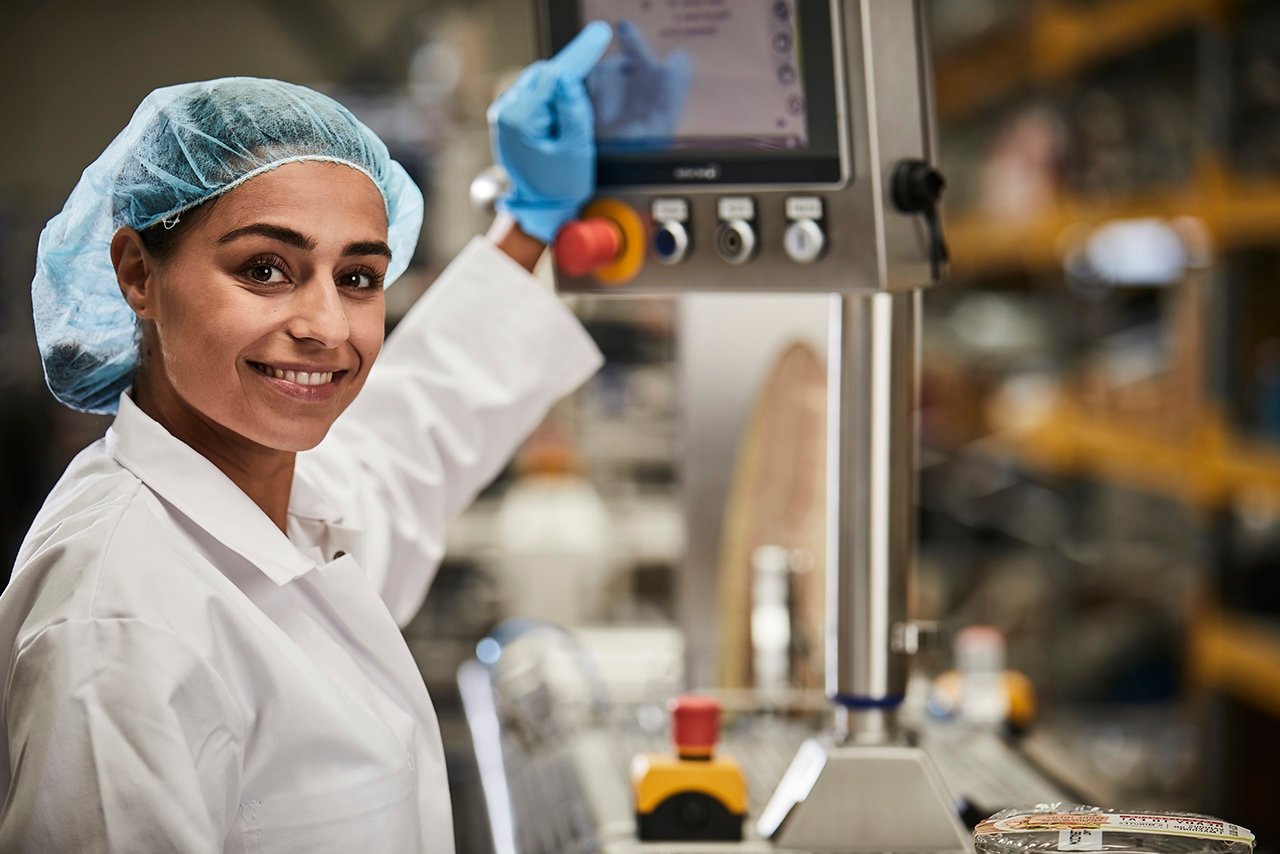 Mitarbeiterin bedient eine Fleischverpackungslinie über ein Touchpanel