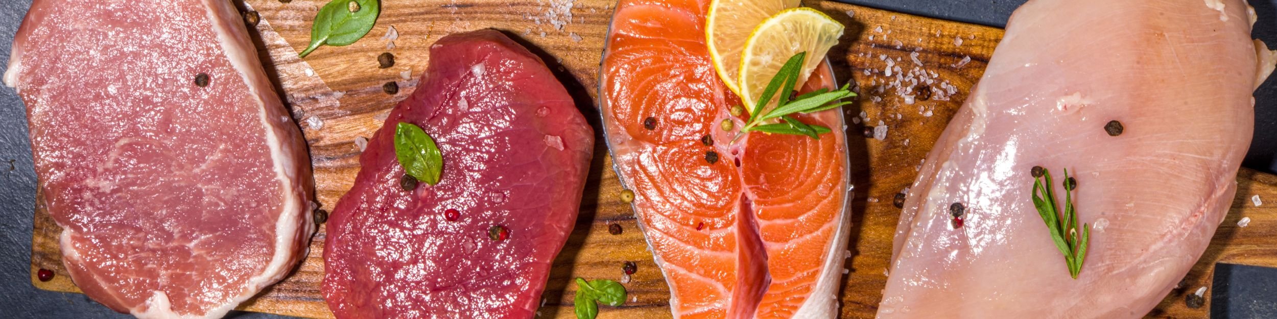 Fresh cuts of meat and seafood on a wooden board – representing JASA Packaging Solutions for meat and seafood packaging