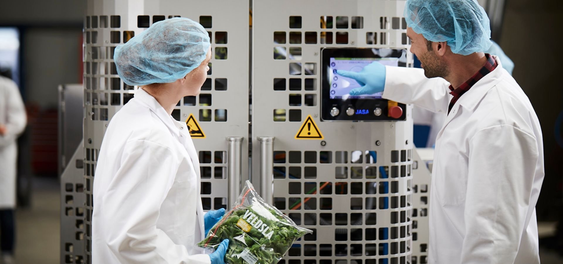 Bediener prüfen eine JASA Verpackungsmaschine in einer Lebensmittel-Verpackungslinie